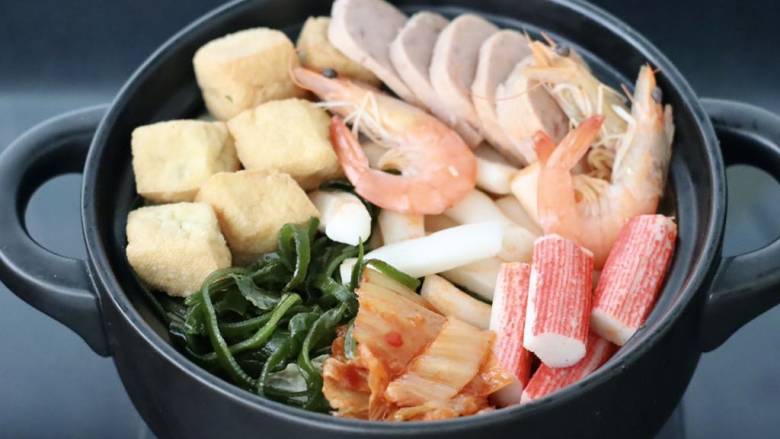 韩式年糕部队火锅,锅底平铺油豆腐和午餐肉，虾和蟹棒，<a style='color:red;display:inline-block;' href='/shicai/ 4872'>海带丝</a>和年糕条。