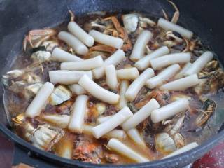 家常炒螃蟹,放入年糕条翻拌均匀，中小火继续再煮5-8分钟。