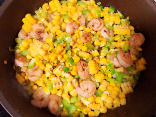 玉米虾仁蛋炒饭,下入玉米粒和青椒丁，加入盐、生抽翻炒均匀。