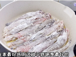 酱烧豆腐鱼教程,把粘好粉的鱼放在锅中煎。