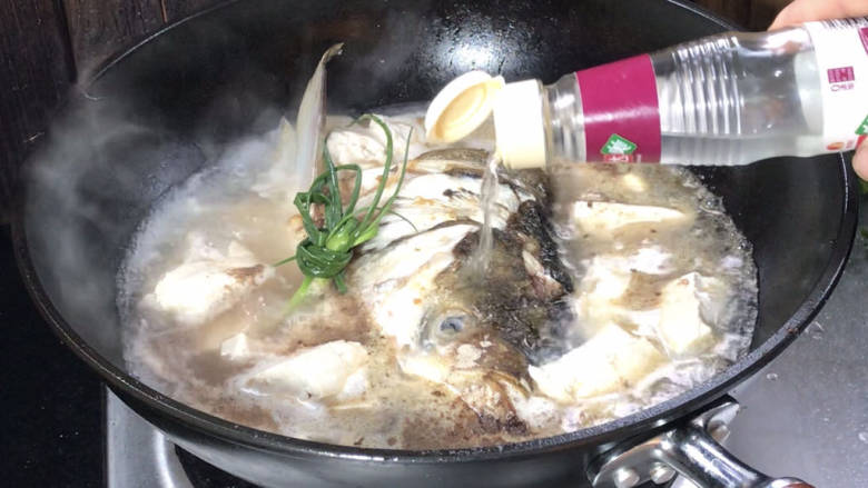 鱼头炖汤,接着加入盐、胡椒粉和料酒，煮沸后继续煮2分钟，再盖上盖子煮10分钟