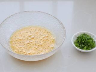 玉米虾仁蛋炒饭,鸡蛋磕入大碗中，充分搅打均匀至起泡状态，香葱切葱花备用。