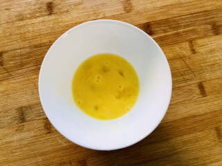 玉米虾仁蛋炒饭,碗里打入一个鸡蛋，用筷子搅打均匀。