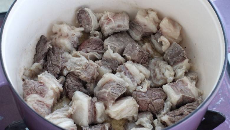 红焖牛肉煲,锅中倒入适量食用油烧热，下牛肉翻炒变色断生。