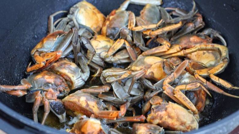 家常炒螃蟹,再将螃蟹的正反面煎至变色，拨到锅的一侧。