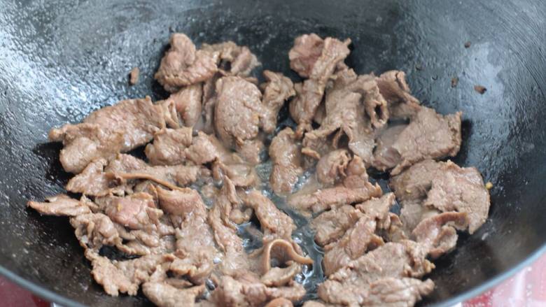 滑蛋牛肉,把牛肉中的食用油沥出倒回锅中，牛肉片铺到上面开火。