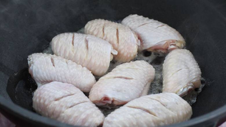 蒜香焖翅,锅中倒少许食用油烧热，将鸡翅依次排放锅中改小火煎制。
