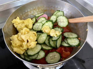 番茄黄瓜炒蛋,加入黄瓜片、炒鸡蛋和肉花肠，中火翻炒一分钟