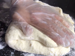淡奶油小餐包,案台上撒上少许干粉，取出发酵好的面团，按压排气