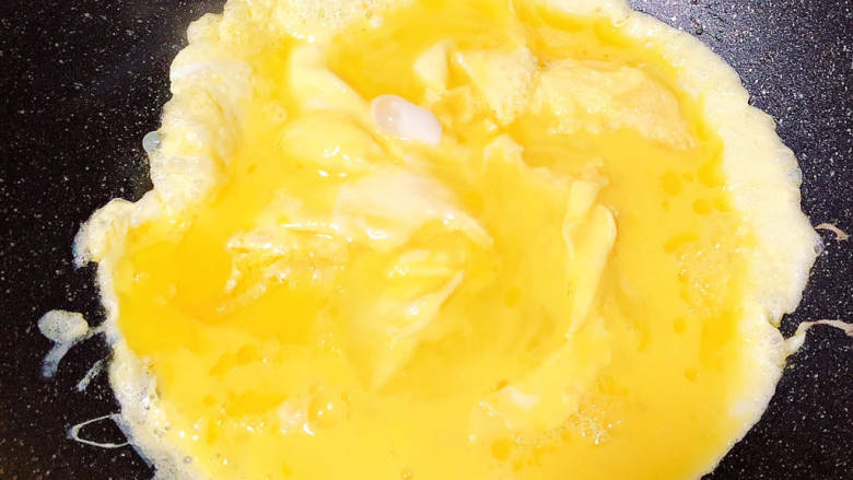 包菜粉丝炒鸡蛋,锅中倒入油，加热至六成热，倒入蛋液炒熟。