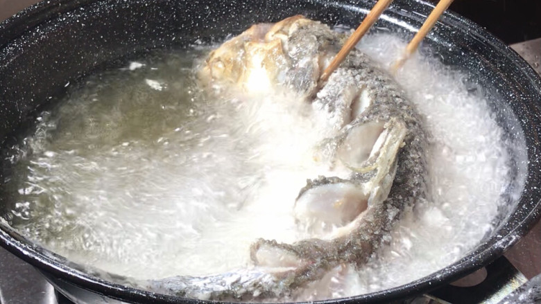 糖醋脆皮鱼,再慢慢的把整个鱼放入油中，用筷子定型