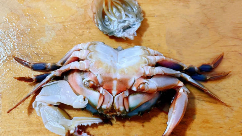 家常炒螃蟹,先将螃蟹的尾部腮取下再将螃蟹一切为二处理里面的杂质