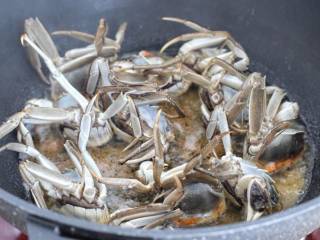 家常炒螃蟹,锅中倒入食用油烧热，先把切面朝下放进锅中煎至定型。
