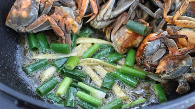 家常炒螃蟹,放入葱段和姜丝炒出香味，再混合螃蟹翻炒均匀。